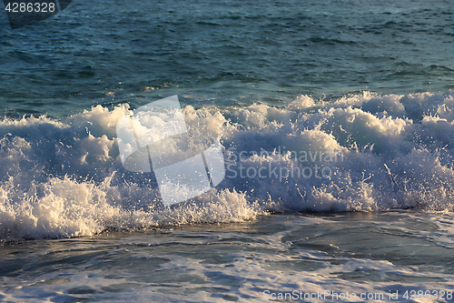 Image of Sea waves and white foam on the evening coast