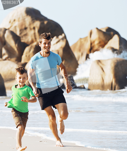 Image of happy family on beach playing, father with son walking sea coast