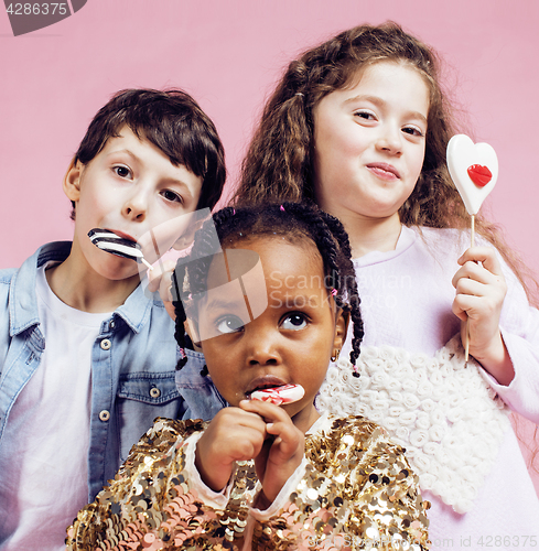 Image of lifestyle people concept: diverse nation children playing together, caucasian boy with african little girl holding candy happy smiling 