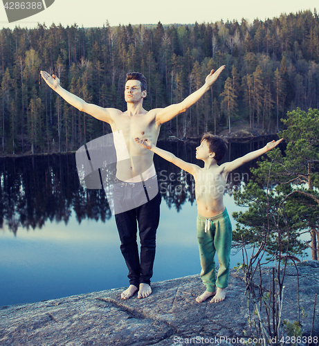 Image of middle age man with little cute son doing sport yoga on the top of the mountain together, happy family lifestyle people outdoor, summer wild nature for training 