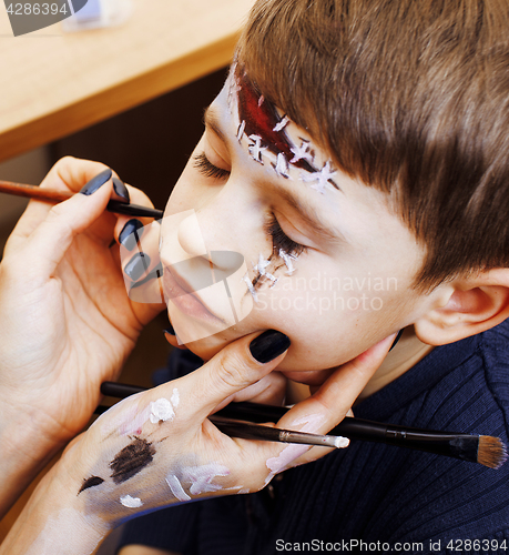 Image of little cute child making facepaint on birthday party, zombie Apo