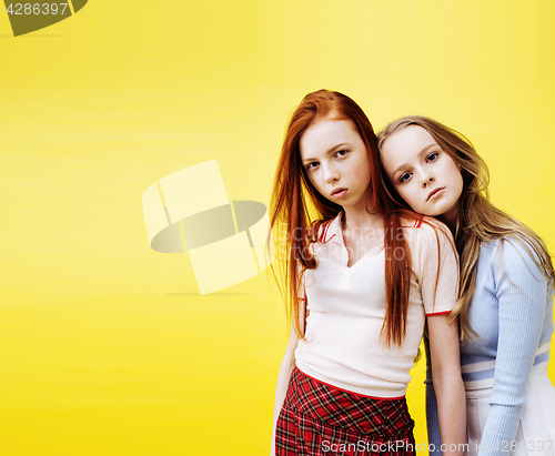 Image of lifestyle people concept: two pretty young school teenage girls having fun happy smiling on yellow background 