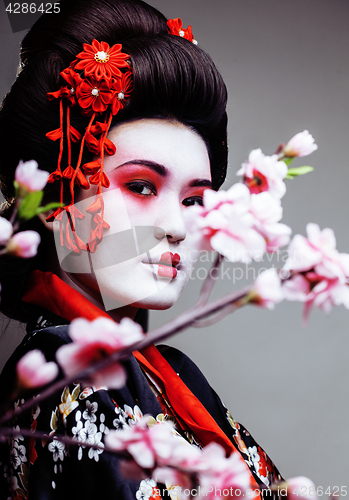 Image of young pretty geisha in kimono with sakura and red decoration design on white background