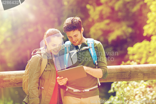 Image of happy couple with backpacks and tablet pc outdoors