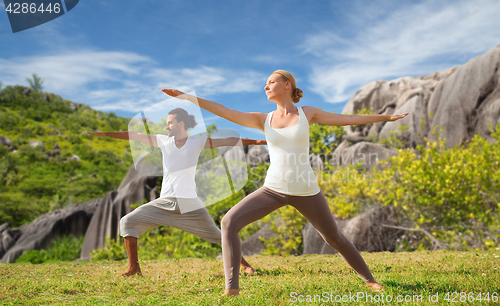 Image of couple making yoga in warrior pose at seaside