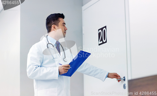 Image of doctor with clipboard opening hospital ward door