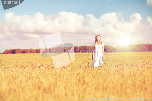 Image of happy young woman in flower wreath on cereal field