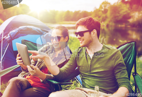 Image of happy couple with tablet pc at camping tent