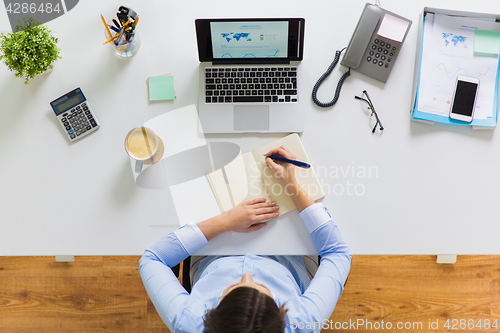 Image of businesswoman writing to notebook at office