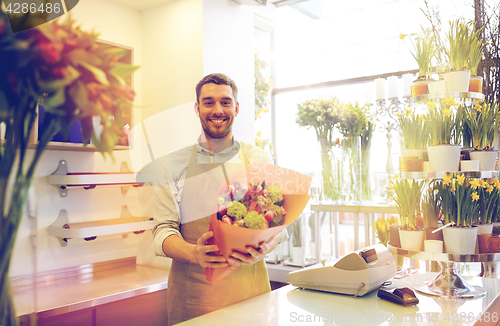 Image of smiling florist man making bunch at flower shop