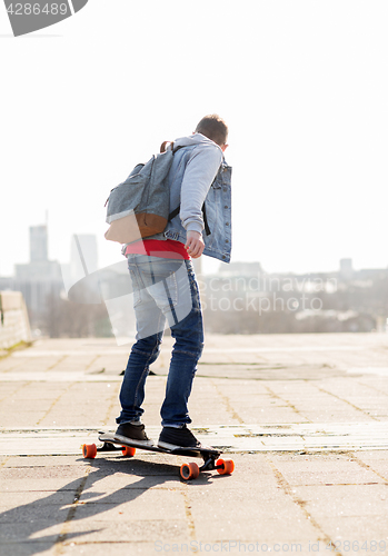 Image of happy young man or teenage boy riding on longboard
