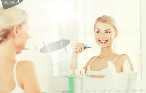 Image of woman with toothbrush cleaning teeth at bathroom