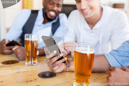 Image of male friends with smartphone drinking beer at bar