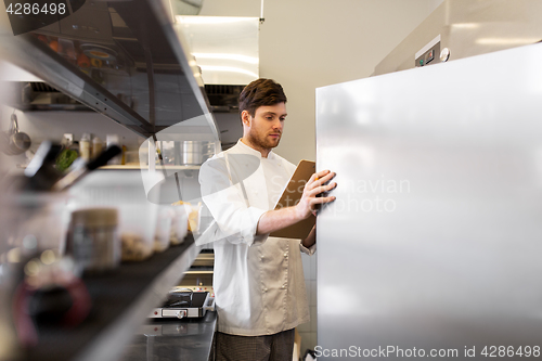 Image of chef with clipboard doing inventory at kitchen