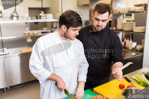 Image of two chefs cooking food at restaurant kitchen