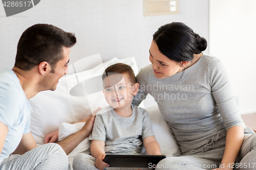 Image of happy family with tablet pc in bed at home