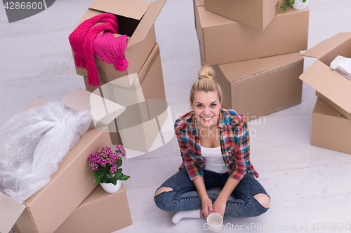 Image of woman with many cardboard boxes sitting on floor