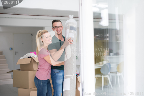 Image of couple carrying a carpet moving in to new home