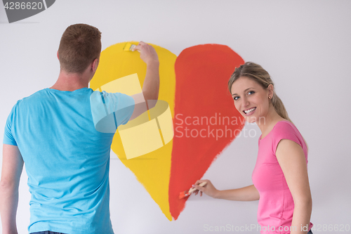 Image of couple are painting a heart on the wall