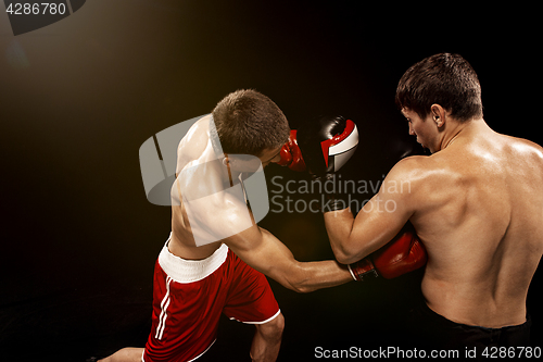 Image of Two professional boxer boxing on black background,