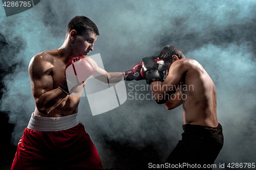 Image of Two professional boxer boxing on black smoky background,