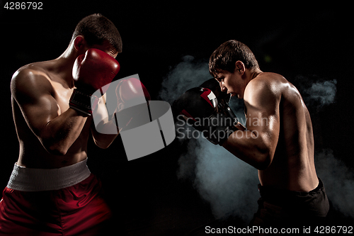 Image of Two professional boxer boxing on black smoky background,