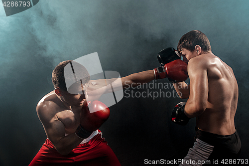 Image of Two professional boxer boxing on black smoky background,