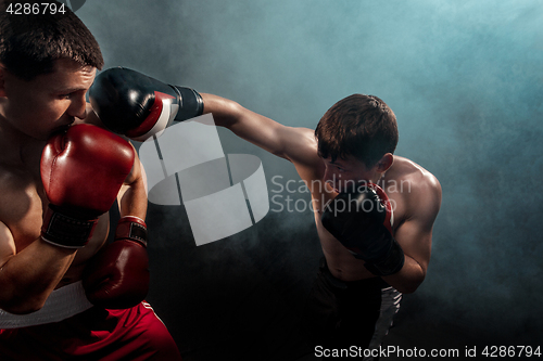 Image of Two professional boxer boxing on black smoky background,