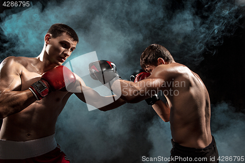 Image of Two professional boxer boxing on black smoky background,