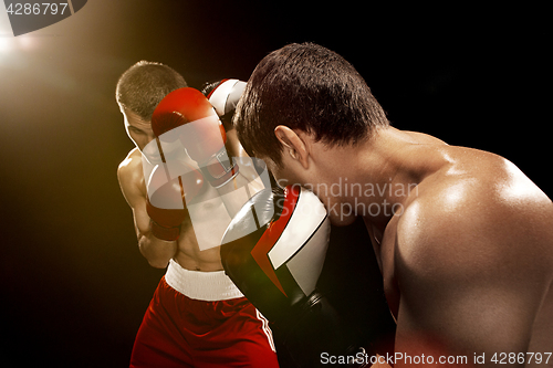 Image of Two professional boxer boxing on black background,