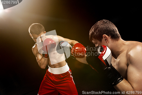 Image of Two professional boxer boxing on black background,