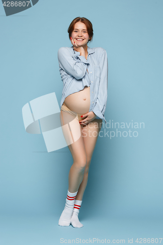 Image of Young beautiful pregnant woman standing on blue background