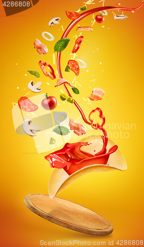 Image of Tasty pizza and falling ingredients on orange background