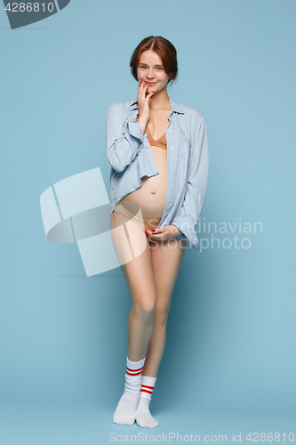 Image of Young beautiful pregnant woman standing on blue background