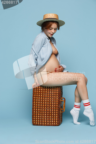 Image of Young beautiful pregnant woman sitting on blue background