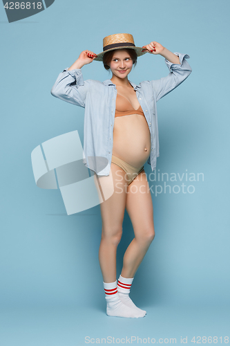 Image of Young beautiful pregnant woman standing on blue background