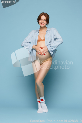 Image of Young beautiful pregnant woman standing on blue background