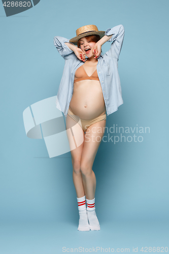 Image of Young beautiful pregnant woman standing on blue background