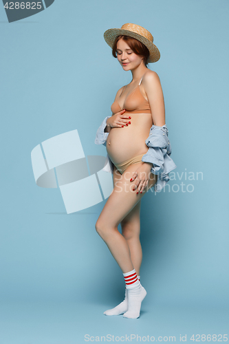 Image of Young beautiful pregnant woman standing on blue background