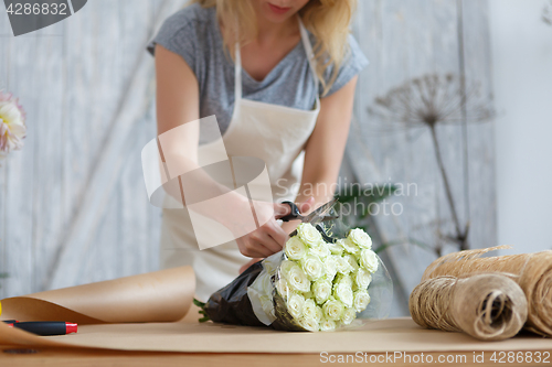 Image of Florist makes bouquet of roses