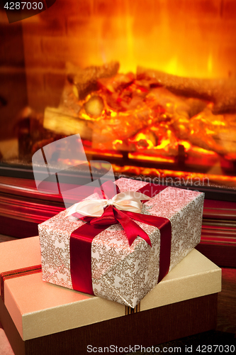 Image of Christmas gift box with near fireplace