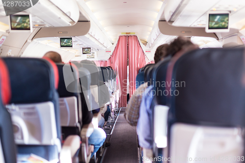 Image of Interior of commercial airplane with passengers on seats during flight.