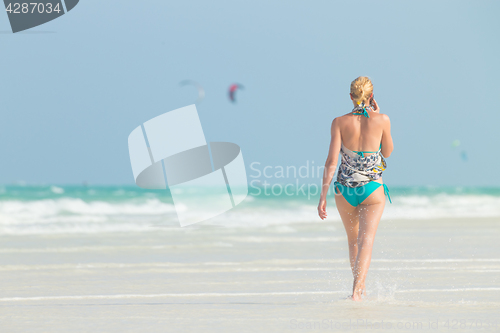 Image of Happy woman having fun, enjoying summer, walking joyfully on tropical beach, Zanzibar, Tanzania.