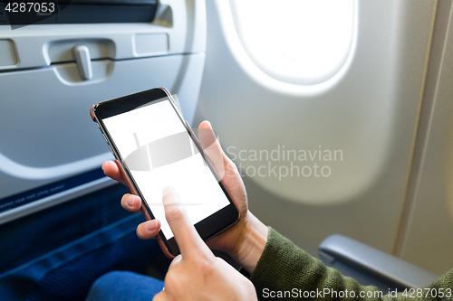 Image of Holding digital mobile phone at airplane