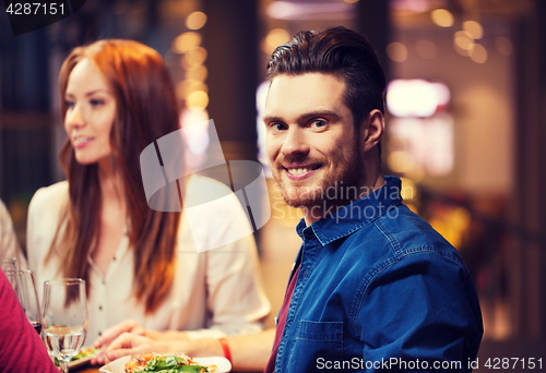 Image of happy man with friends having dinner at restaurant