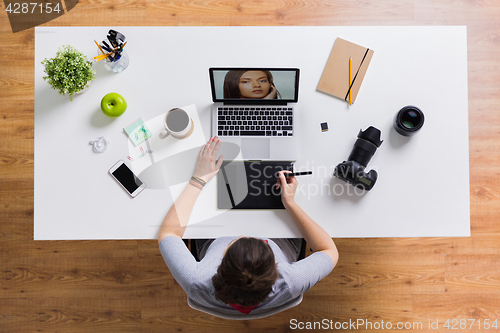 Image of woman with camera working on laptop at table