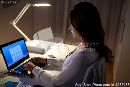 Image of businesswoman with laptop at night office