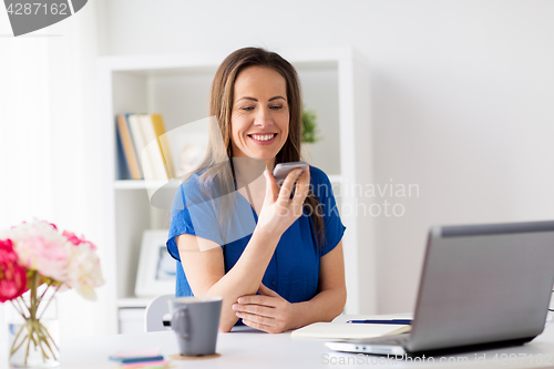 Image of woman using voice recorder on smartphone at office