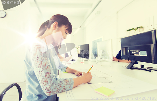 Image of architect woman drawing on blueprint at office