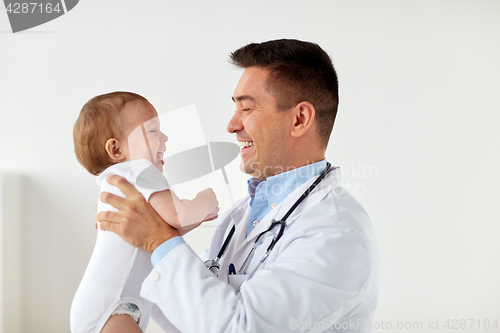 Image of happy doctor or pediatrician with baby at clinic
